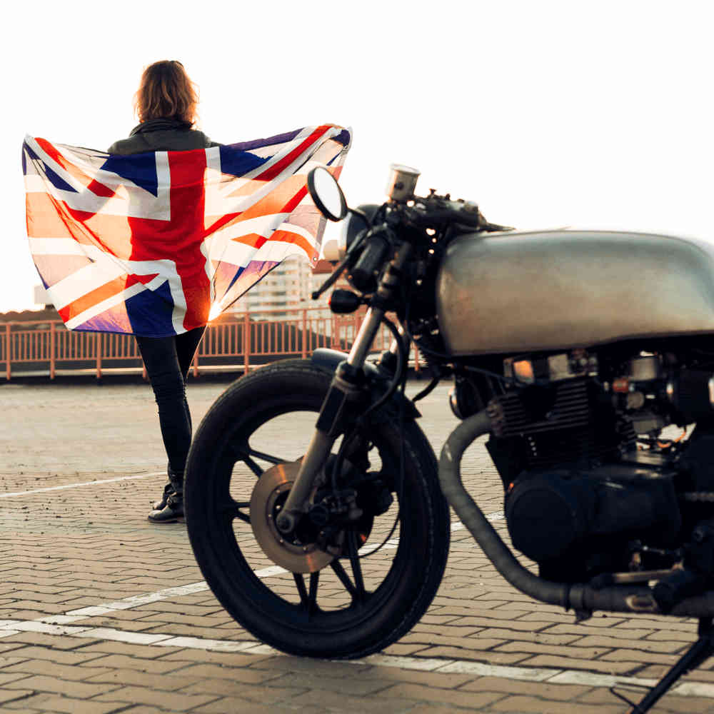 A woman stands next to a motorbike with a Union flag
