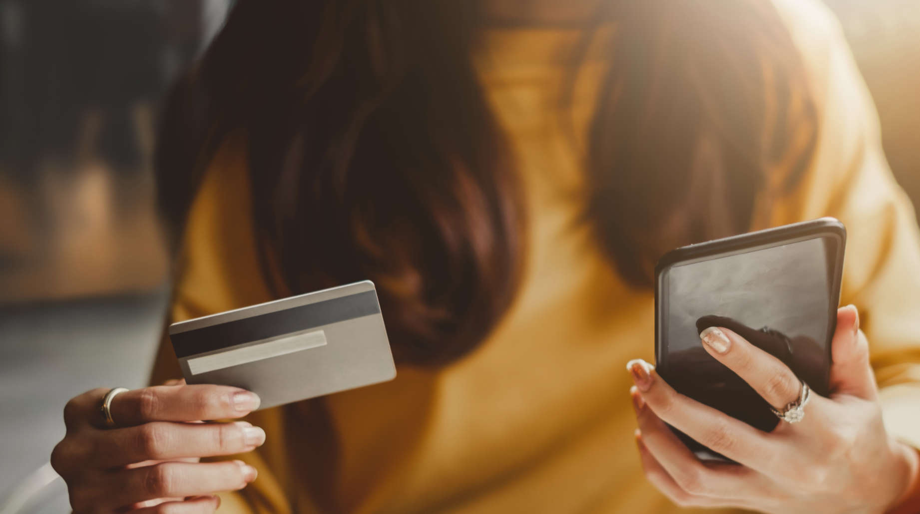 Woman with credit card and mobile phone looking to pay for something online