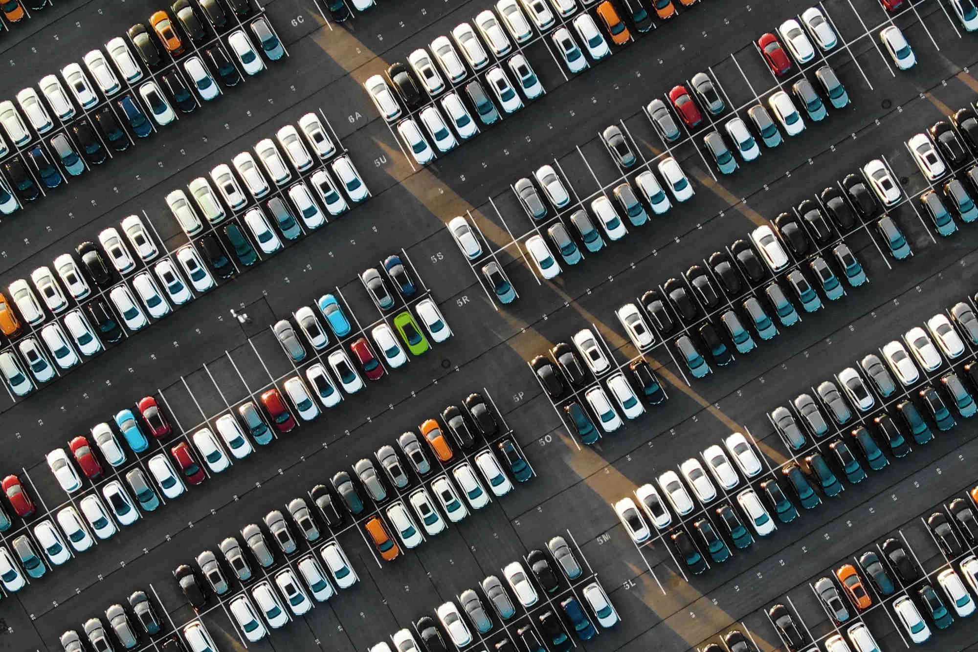 Aerial shot of lines of cars parked at an angle in a car park